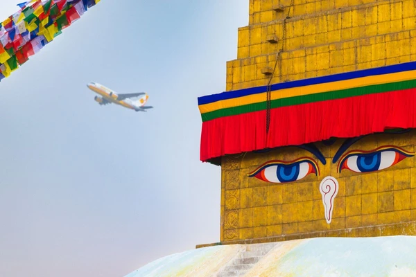Boudhanath-Stupa mit Gebetsfahnen und Flugzeug am Himmel in Kathmandu, Nepal