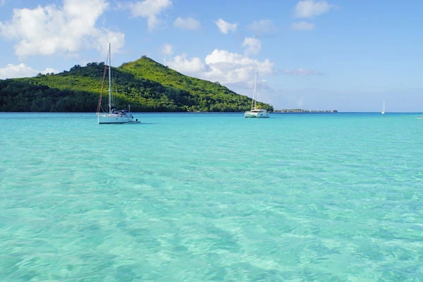 Farbenspiel in der Lagune von Bora Bora mit Booten und Bergansichten