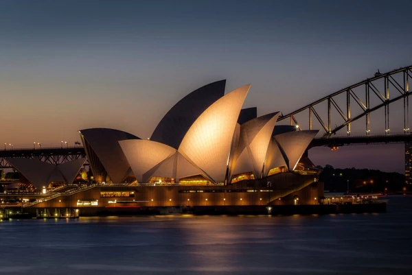 Die beleuchtete Oper in Sydney am Abend mit Blick auf die Sydney Harbour Bridge