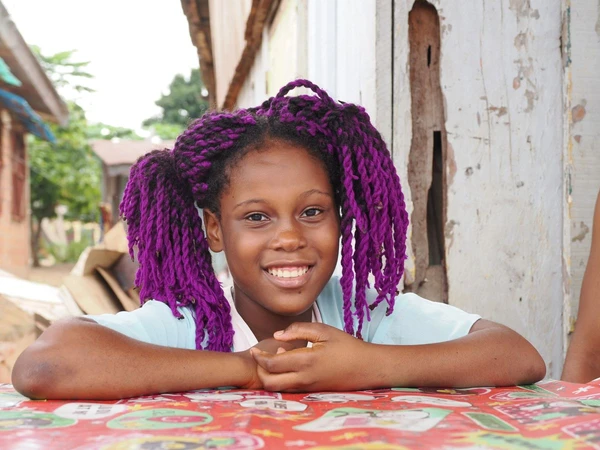 Kleines Mädchen in Kongo mit lila Haaren und fröhlichem Lächeln